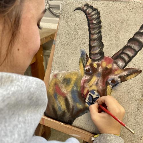 Schülerin malt einen bunten Steinbock in Freskotechnik